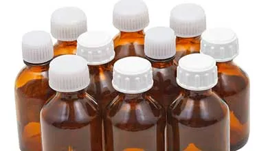 Several small brown glass medicine bottles with white ribbed caps on a white background.