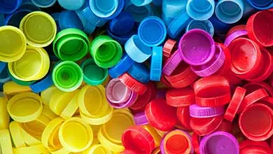 Close-up of densely packed plastic bottle caps in bright yellow, green, blue, magenta, and red.