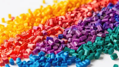Multicolored plastic resin pellets arranged in small piles on a white background.