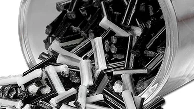 Close-up of a clear container spilling small black-and-white rod-shaped pellets.