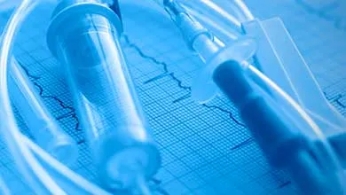 "Clear medical tubing, syringe, and connector components arranged on a blue medical monitoring background, illustrating biopharmaceutical fluid transfer and delivery systems. "